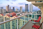 View of a sunny Isles apartment balcony overlooking the city and ocean, ideal for renting a one-bedroom home.