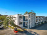 Exterior view of SoDo Flats apartments in Orlando, featuring mature landscaping and parking area.