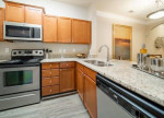 Modern kitchen with stainless steel appliances and granite countertops in Rose Heights Apartments.