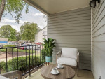 Cozy private balcony with seating and coffee cups, overlooking landscaped grounds at Crosswinds Apartments.