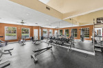 Modern fitness center at The Park at Via Veneto with gym equipment and windows overlooking a serene lake.