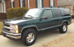 1996 Chevrolet Tahoe LT RWD in dark green parked outside a house, showing low mileage and clean exterior.
