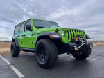 2018 Jeep Wrangler Rubicon 4WD in bright green, parked outdoors showcasing its off-road capabilities.