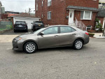 2017 Toyota Corolla LE with backup camera parked on the street, showcasing its clean design and efficiency.
