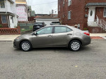 Side view of a 2017 Toyota Corolla LE in gray color parked on a street, showcasing its design and wheels.