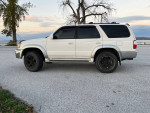 2002 Toyota 4Runner SR5 V6, white SUV parked by a lake, showcasing its well-maintained exterior and black rims.