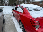2015 Chevrolet Sonic LTZ parked in snow, showcasing its sleek red exterior and snowy surroundings.
