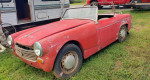 1962 MG Midget convertible for parts or restoration, parked on grass with a vintage aesthetic.