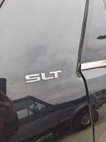 Close-up of the SLT badge on a 2012 GMC Acadia, highlighting its AWD capability and rust-free condition.