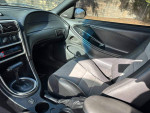 Interior view of a 1994 Ford Mustang GT with black leather seats and modern dashboard features