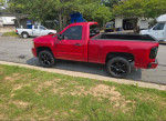 2007 Chevrolet Silverado 1500 Classic LT1 in red, parked on the street, showcasing its sleek design and black wheels.