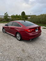 2015 Hyundai Sonata Limited in red parked on gravel, showcasing its sleek design and ready for driving adventures.