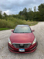 Front view of a red 2015 Hyundai Sonata Limited parked on a gravel road, showcasing its sleek design.