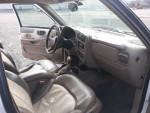 Interior view of a 1999 Chevrolet TrailBlazer showing worn leather seats and dashboard features.