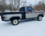 1985 Ford F150 stepside truck parked in snow, featuring a unique two-tone finish and sturdy frame.