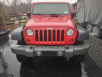 Front view of a 2009 Jeep Wrangler, red exterior, in good condition with minor dings and included soft top.