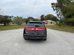Rear view of a 2010 Lincoln MKT with low mileage, showcasing its sleek design on a residential street.