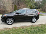 Side view of a 2014 Honda CR-V EX-L in black parked on a driveway, showcasing its sleek design and alloy wheels.