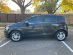 2014 Chevrolet Sonic LT hatchback in black, showcasing aluminum wheels and a sleek profile, parked outdoors.