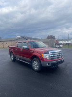 2013 Ford F-150 Lariat 4WD truck in red with chrome accents parked on a paved surface.