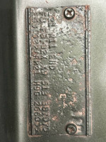 Close-up of the identification tag on a 1969 Plymouth Roadrunner showing surface rust and details.