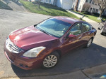 2012 Nissan Altima in maroon color with 129k miles, good engine and transmission, parked in residential area.