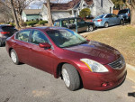 2012 Nissan Altima with 98,000 miles parked on a residential street, showcasing its maroon color and good condition.