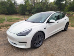 2021 Tesla Model 3 Standard Range Plus in white with black interior parked on gravel road