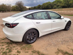 2021 Tesla Model 3 Standard Range Plus in white with black leather interior, showing rear and side view.