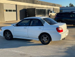 2002 Subaru Impreza WRX AWD in white parked, featuring manual transmission and sporty design.