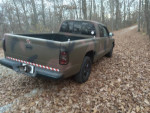1997 Dodge Dakota Sport 4WD parked on a leaf-covered road, showcasing its camouflaged paint and compact design.