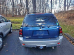 Blue 2006 Chevrolet TrailBlazer LT SUV parked in a leafy area, features cracked windshield and decals.
