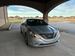 2011 Hyundai Sonata Limited FWD parked under a shelter, showcasing its sleek design and silver color.