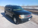 2003 GMC Yukon Denali AWD parked on a road, showcasing its sleek design and well-maintained exterior.