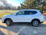 Side view of a white 2015 Nissan Rogue SL, showcasing its sleek design and low mileage in a scenic outdoor setting.