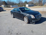 2012 Cadillac CTS parked on gravel, featuring a sleek design and shiny alloy wheels.