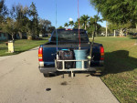 Blue 2000 Chevy Silverado LS with fishing gear and accessories on the back parked on a sunny street.