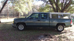 Side view of a well-maintained 2002 Chevrolet Silverado 1500 in green with a camper shell.