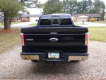 2011 Ford F-150 rear view showing truck bed and tailgate, with some rust and gravel driveway background.