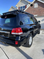 2008 Toyota Land Cruiser with roof rack parked in driveway, showcasing clean design and V8 engine.
