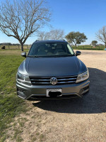 Front view of a gray 2018 Volkswagen Tiguan SE 4Motion AWD parked outdoors with trees in the background.
