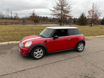 2013 Mini Cooper in red, excellent condition, parked on a road with grass and trees in the background