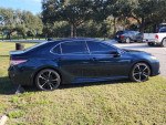 2020 Toyota Camry XSE FWD in Galactic Aqua color parked on grass, showcasing sleek design and stylish wheels.
