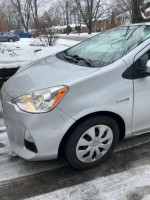 2014 Toyota Prius C hybrid in silver parked on snow-covered street, showing front detail and low mileage.