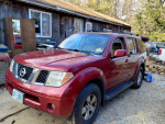 2007 Nissan Pathfinder in maroon with 4x4 capability parked outdoor, featuring roof rack and alloy wheels.