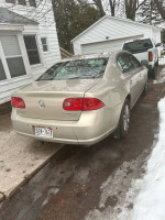 2009 Buick Lucerne CXL FWD parked in a residential area, showcasing its beige exterior and good condition.