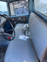 Interior of a 1965 International Harvester D100 truck, featuring a simple dashboard and worn seats.