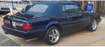 1993 Ford Mustang LX convertible in royal blue with polished wheels and black top parked outside.
