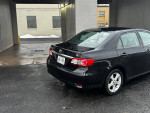Black 2013 Toyota Corolla LE parked, showcasing its great condition and features like power windows and moonroof.