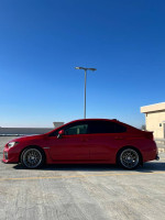 2016 Subaru WRX Limited in red parked under clear blue sky, showcasing modified wheels and sporty profile.